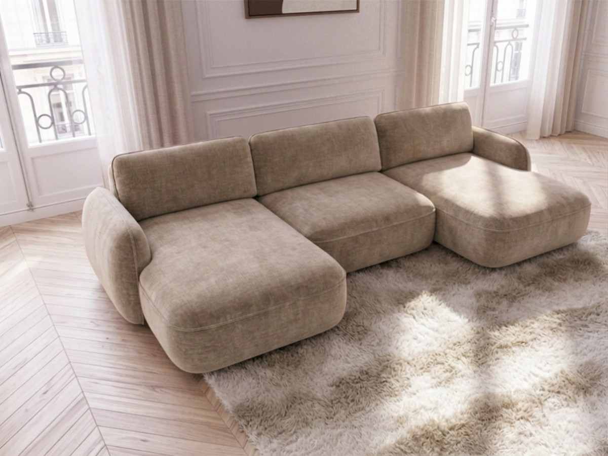 Canapé Céleste beige vu de trois quarts, avec les coutures arrondies de l’assise et des accoudoirs