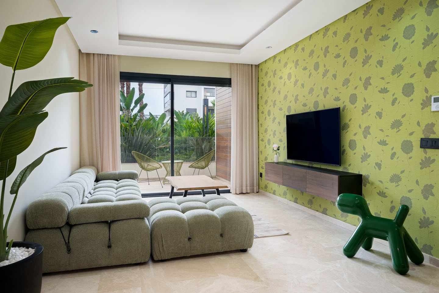 Salon du duplex avec canapé vert, mur à motifs végétaux et sculpture verte