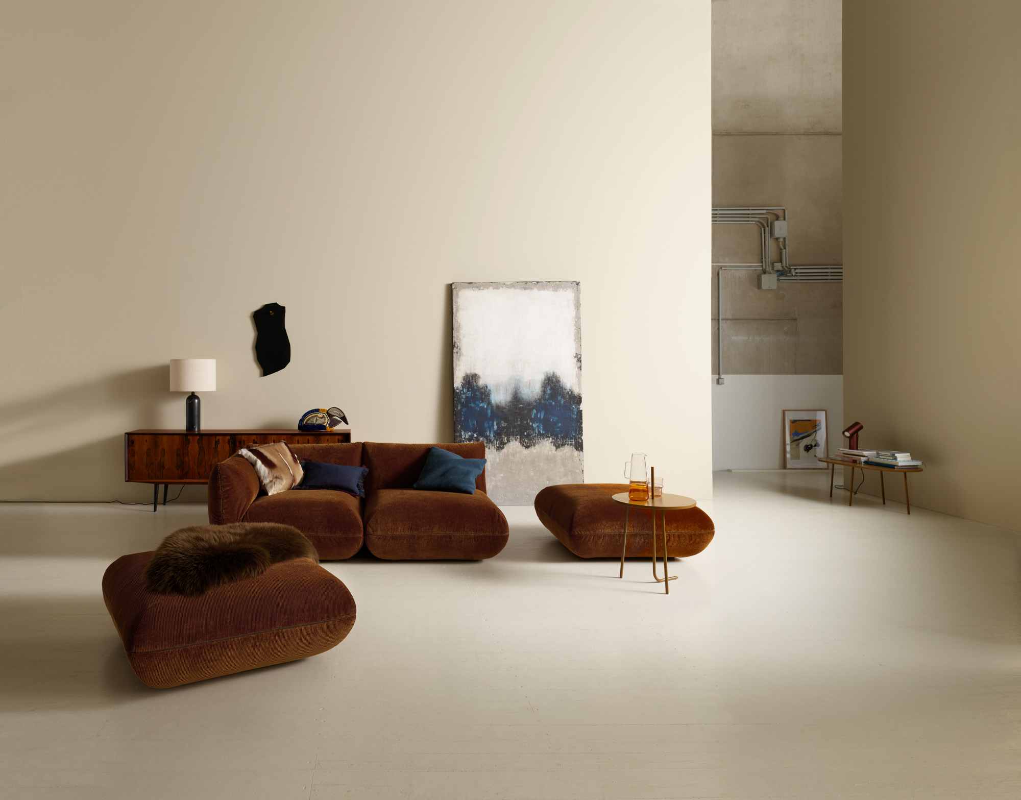 Canapé Jalis et pouf en velours côtelé brun dans un salon aux murs beige.