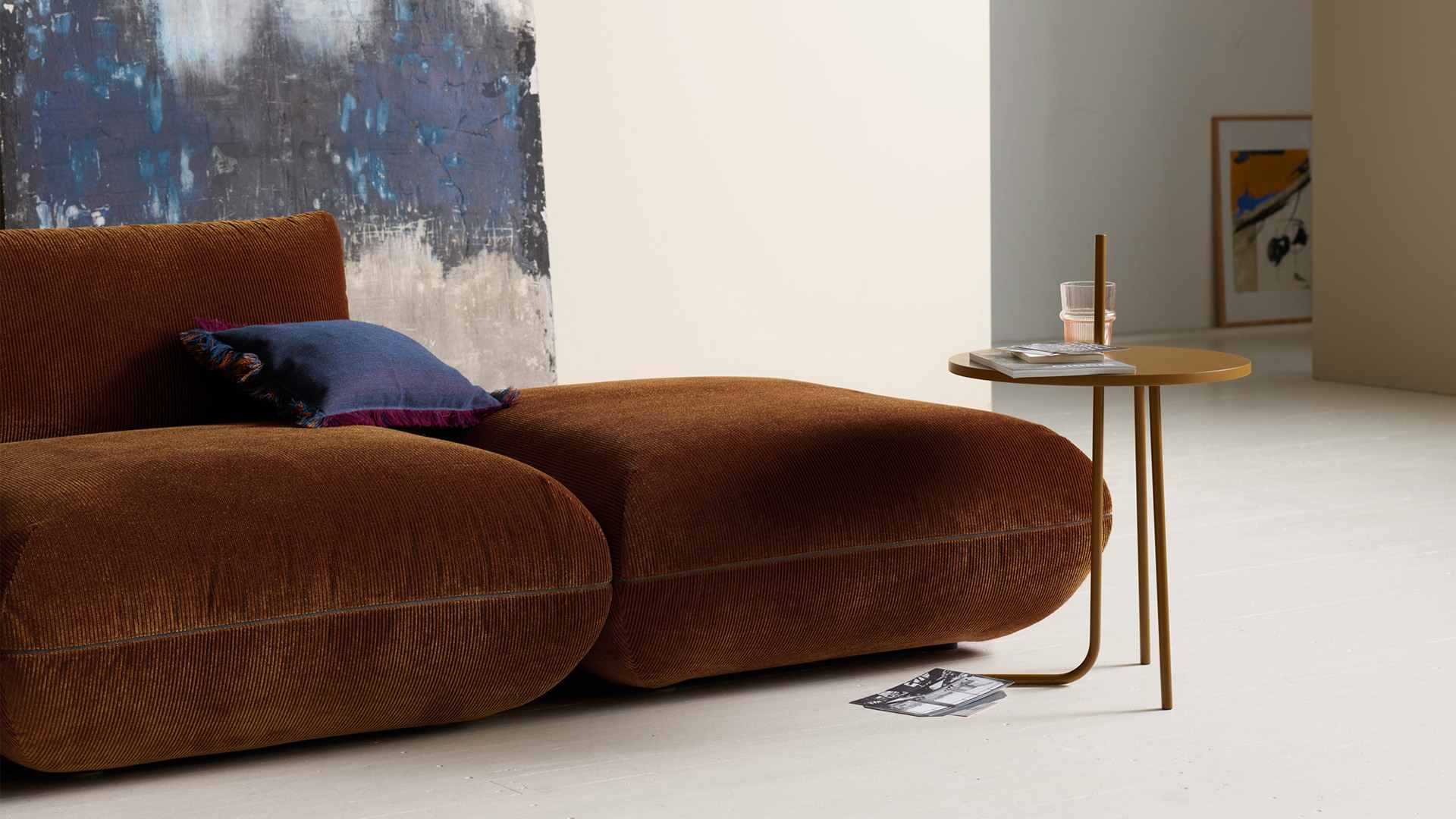 Assises Jalis en velours côtelé brun, vues de trois quarts avec un coussin bleu.