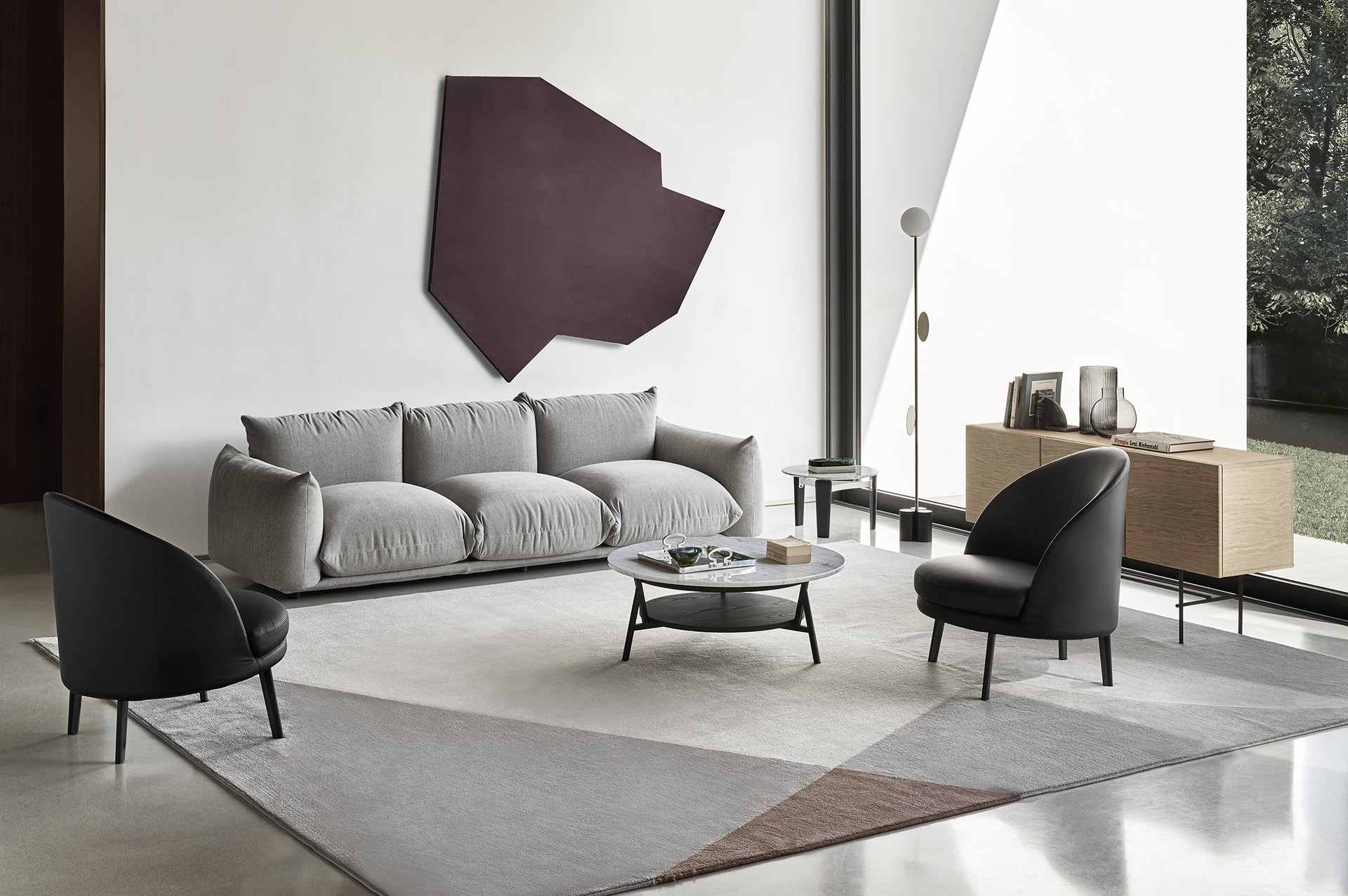 Canapé Marenco gris dans un salon contemporain en béton et verre