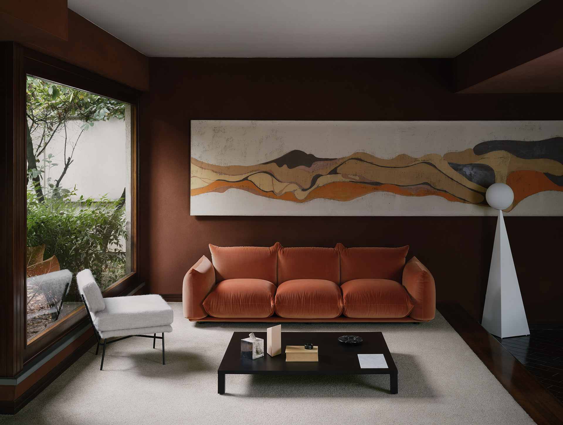 Canapé Marenco orange dans un salon ouvert sur un jardin