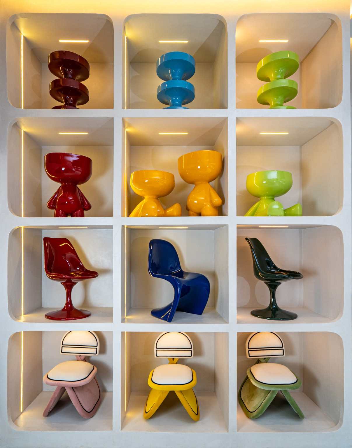 Mobilier coloré et chaises exposés dans les niches éclairées du showroom Studio Amsaï