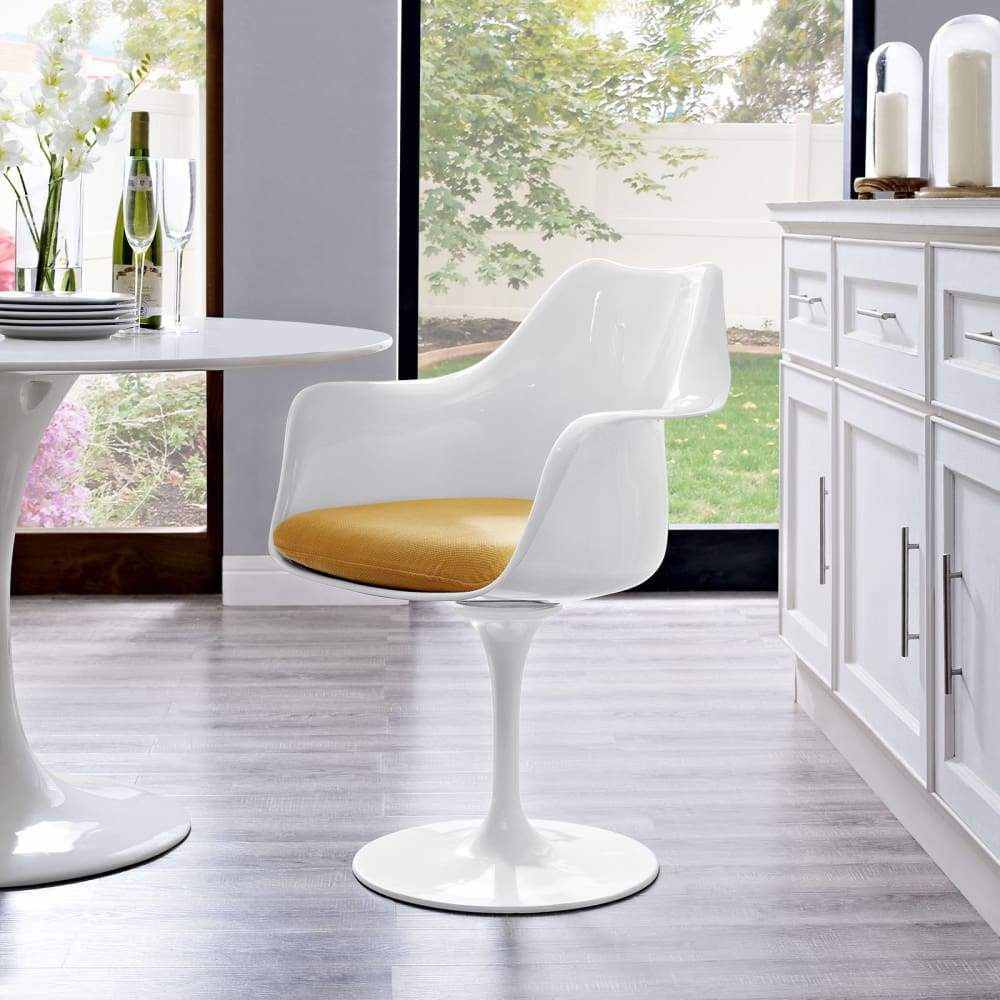 Fauteuil Tulipe blanc à coque nue et petit coussin moutarde dans une pièce lumineuse donnant sur le jardin.